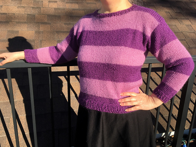 Woman wearing hand knit pullover with large stripes in two shades of purple