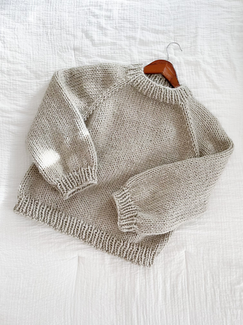 beige knit sweater laid flat on beigh background. pattern featured in super bulky knitting patterns list