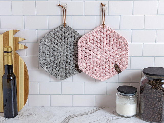 two colors of crochet potholders hanging on ktichen wall
